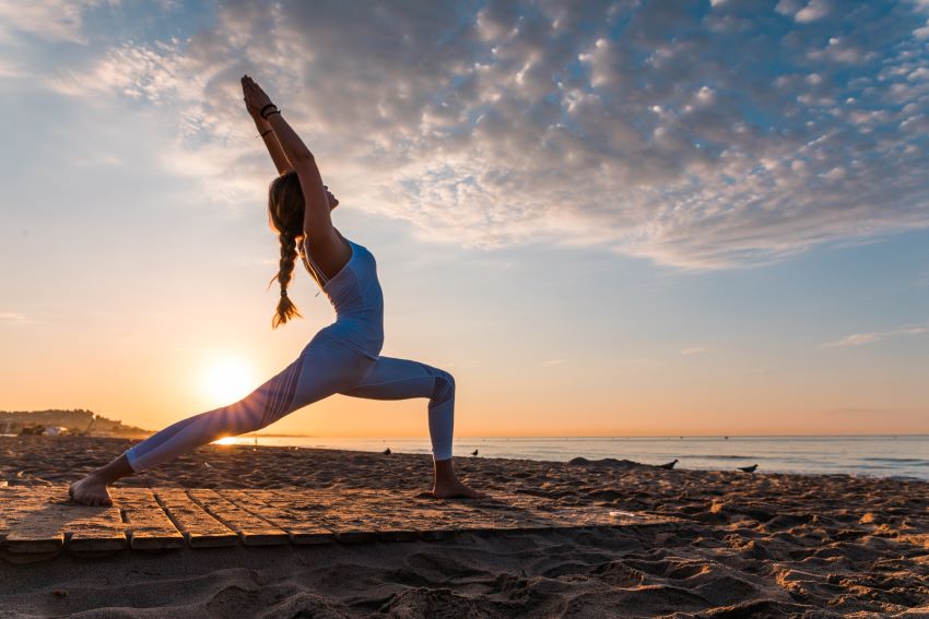 Frau beim Yoga am Wasser in der Abendsonne